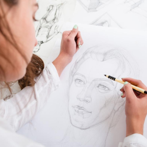 woman sketching face with pencil.