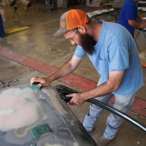 Auto Body student sands car hood.